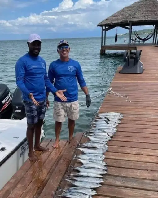 Captain Julio and First Mate Eddie smiling with over 25 blackfin tuna aboard Dos Reyes Roatan deep sea fishing charter in the Caribbean