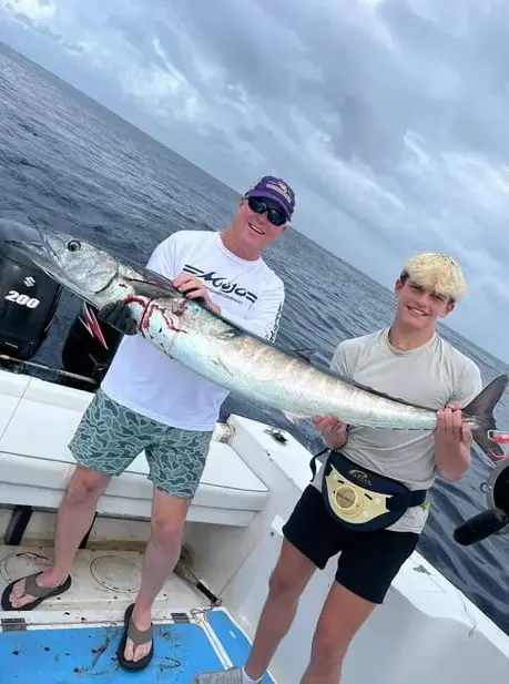 Father and son holding a huge wahoo aboard Dos Reyes Roatan deep sea fishing charter in the Caribbean