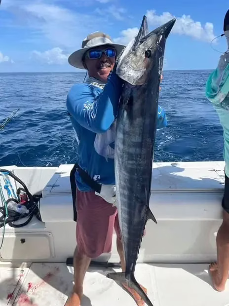 Firstmate Eddie holding a huge wahoo caught while trolling on a Roatan deep sea fishing charter, Dos Reyes Roatan private boat tour, Caribbean fishing adventure