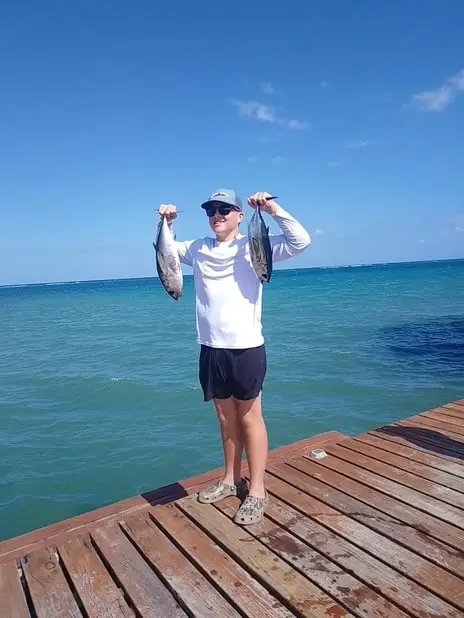 Happy guest holding two Black Fin Tuna, deep sea fishing Roatan, private boat charter, Caribbean adventure, Dos Reyes Roatan