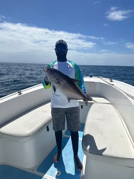 Captain Julio holding a large amberjack caught bottom fishing aboard Dos Reyes Roatan deep sea fishing charter in the Caribbean