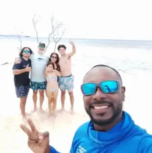 Captain Julio taking a selfie with family at Pigeon Cay during a Dos Reyes Roatan private charter — Caribbean island adventure, snorkeling, and family-friendly boat tours