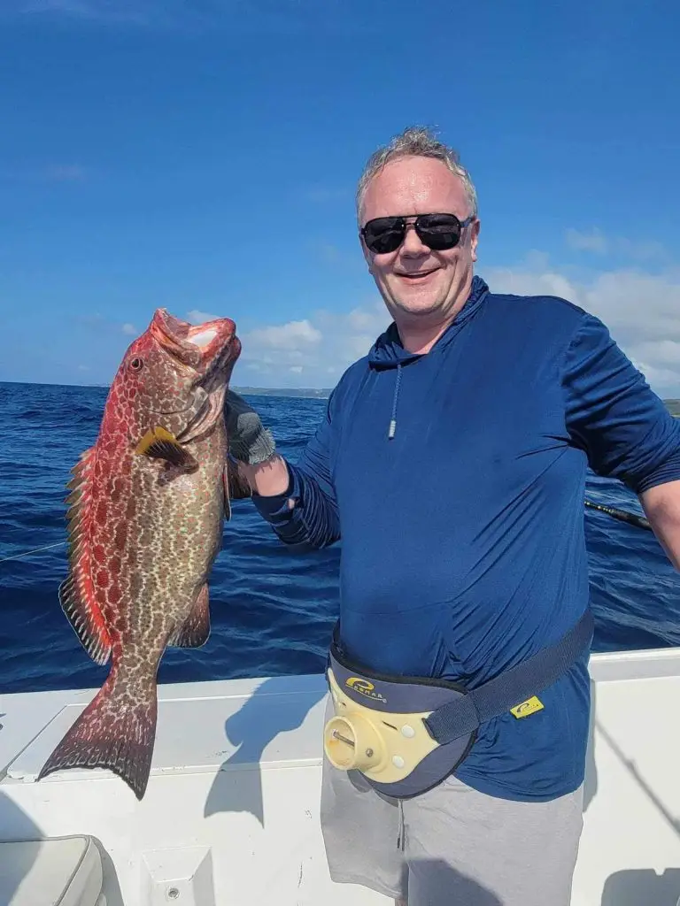 Guest holding strawberry grouper – Dos Reyes Roatan Charter bottom fishing tour in Caribbean waters