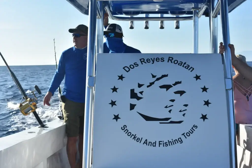 Dos Reyes Roatan Charter boat under way, crew watching bird activity to locate fish during private deep sea fishing tour in Caribbean waters