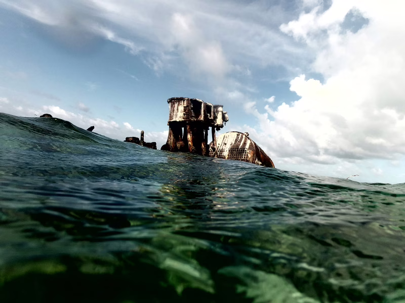 Partially sunken shipwreck rising above the turquoise Caribbean Sea near Roatan